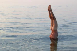 naked-man-doing-a-handstand-underwater-in-a-bay.webp