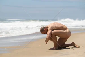 naked-man-kneeling-down-at-the-ocean.webp